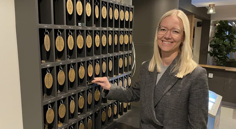 Leende kvinna tar ut nyckel från nyckelskåp.