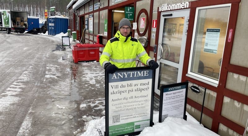 Man som står bakom informationsskyltar på snöig återvinningscentral.