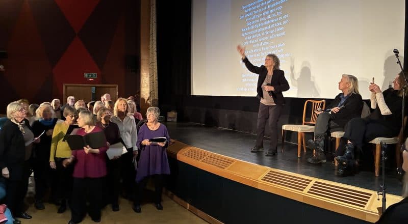 Siw Malmkvist eldar igång publiken från scenen, nedanför står kören och sjunger.