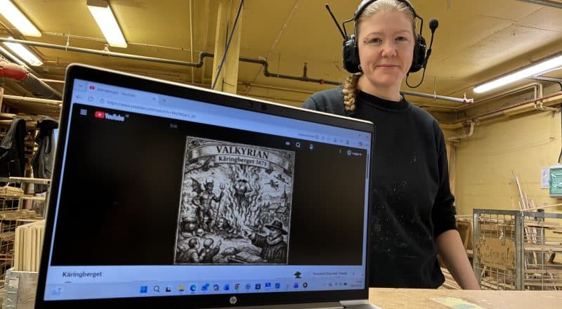 Kvinna i byggarbetsplatskläder bakom en datorskärm där Youtube spelas.