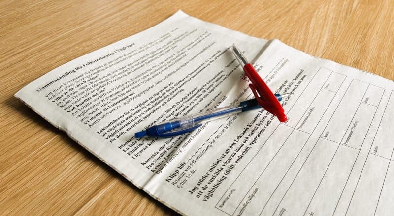 Två pennor på en tidning med blanketten.