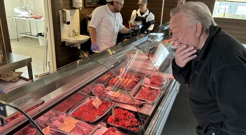Manlig kund står och ser fundersam ut framför köttdisken.