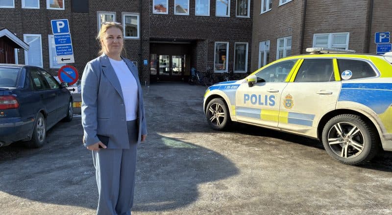 Annica Sandy-Hedin bredvid en polisbil framför skolentrén.
