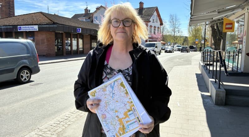Kvinna står uppställd framför kameran med kartpaket i handen.