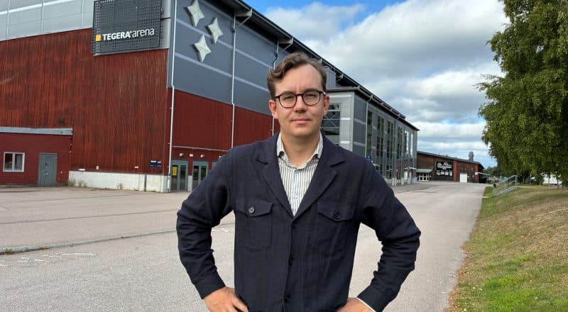 Bestämd man i skjorta och jacka med händerna framför höfterna utanför ishallarna.