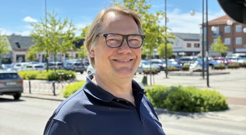 Fredrik Winberg ler på porträttbild framför Torget i Leksand.