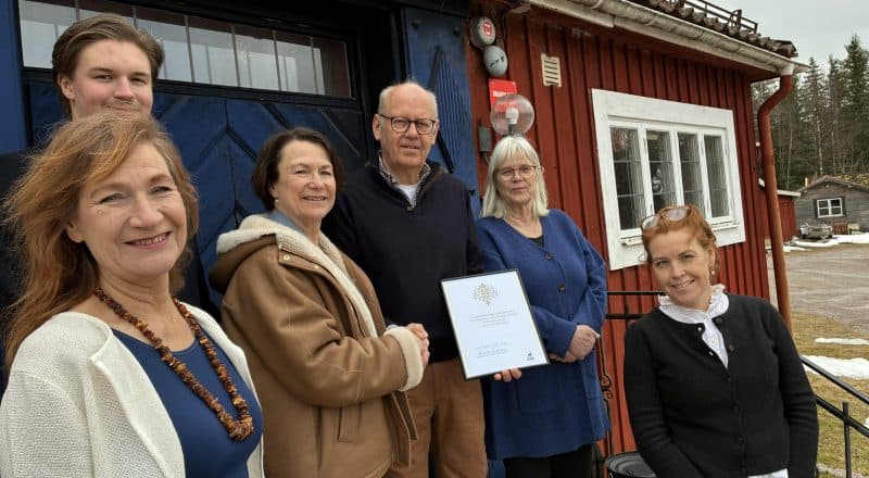 Sex personer står uppställda på bild medan ett inramat diplom delas delas ut.