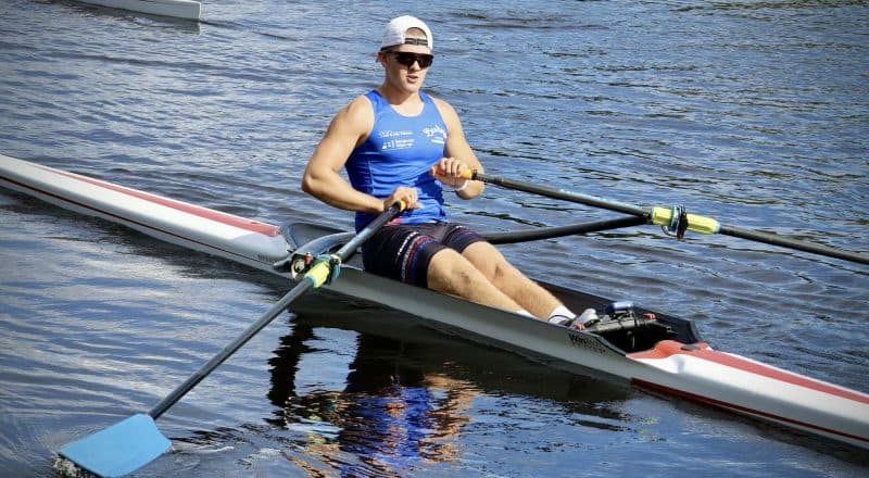 Alfred Änges med solglasögon i sin tävlingsroddbåt på vattnet.