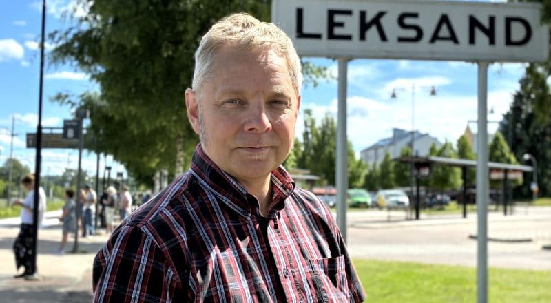 Markus Kummu står i en somrig skjorta vid resecentrumet, framför en stor skylt med texten Leksand.