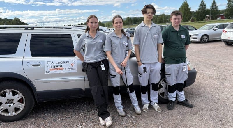 Fyra ungdomar i vårdarbetskläder framför en bil med skyltningen "EPA-ungdom i tjänst"