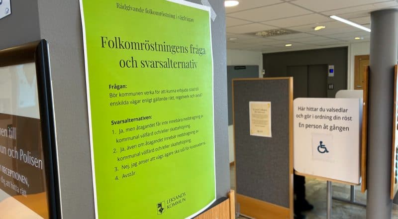 Bild inifrån en vallokal där ett grönt anslag med folkomröstningsfrågan syns störst i bilden.