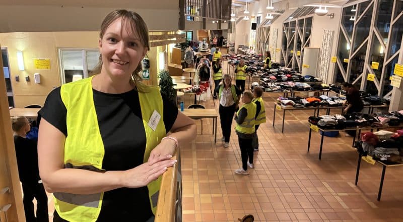 Therese Grannas på trappan i Leksands gymnasium med utsikt över den stora mängden kläder.
